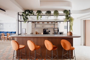 Bed in hotel room with modern bathroom and chair at breakfast table